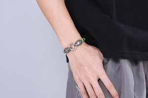 Detailed close-up of a silver dual lion head clasp on a green braided men's bracelet