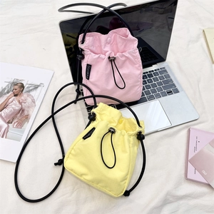 Dettaglio di mini borse a tracolla rosa e gialle con coulisse in tessuto di nylon