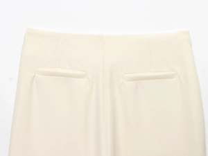 Détail de pantalon crème montrant la couture arrière et les poches passepoilées