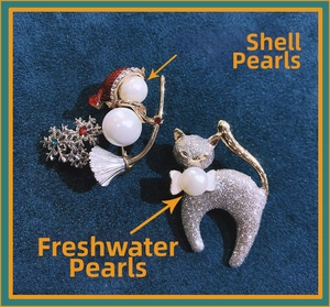 Detailed view of Christmas snowman shell pearl brooch and glittery cat pin accessory