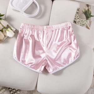 Pink satin shorts with white piping and elastic waistband on a textured background