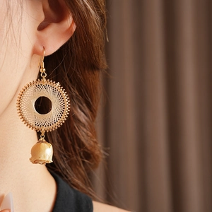 Detailed view of woven round earrings with natural dried flowers on a female model