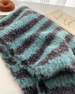 Close-up of soft turquoise and dark grey striped knit scarf with fluffy wool texture