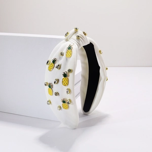 Détail du serre-tête blanc noué avec breloques d'ananas et des strass étincelants
