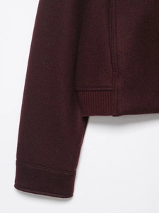 Detail view of burgundy soft cropped jacket showing sleeve cuff and hem stitching quality