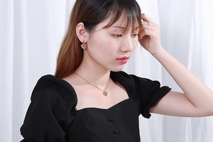 Golden multi-layer heart necklace and earring set shown on a model with white background
