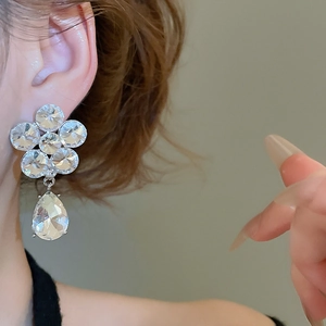 Close-up of sparkling floral water drop earrings with silver needle on a female model