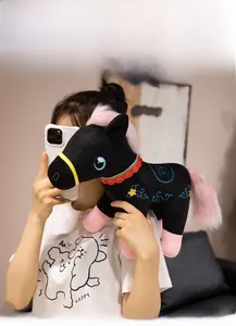 Detail of a black plush pony toy with pink mane and floral cloud embroidery pattern
