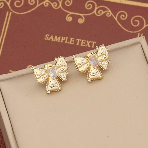 Golden C-shaped bow earrings with sparkling rhinestones and clear zircon on a display box