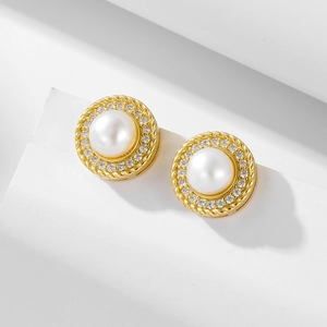 Detailed macro view of pearl stud earrings with zircon inlay and gold rope twist borders