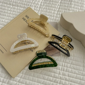 Chic curved shark hair clips in beige, white, black and green colors on white fabric