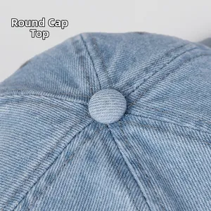 Detail of the round top button on light blue washed denim baseball cap with fine stitching