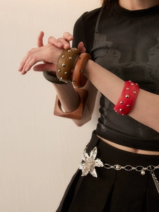 Close-up of retro wooden bangles with metallic studs in round and square shapes