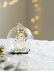 Detail of a glass Christmas tree inside a glowing dome with a gold star and warm lights