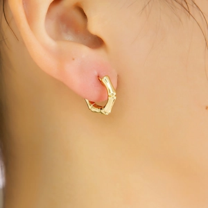 Gros plan détaillé d'une boucle d'oreille dorée en forme de bambou sur l'oreille