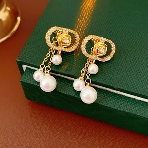 Detailed view of rose flower zircon pearl earrings on a green textured jewelry box