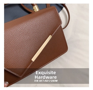Macro shot of brown lychee grain leather with elegant rectangular gold metal hardware details