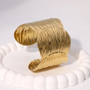 Gold plated stainless steel wide cuff bracelet with wavy texture on white tray