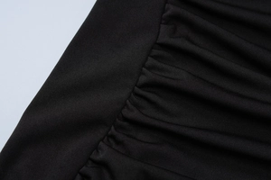 Detailed macro view showing black ruched fabric texture and pleated material craftsmanship