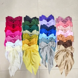 Collection of satin bow hair clips in various colors with long ribbons on a tile floor