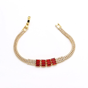 Dettaglio del bracciale dorato con cinque zirconi rossi rettangolari e pavé di diamanti