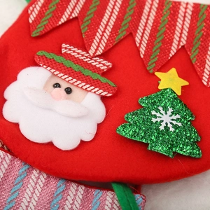 Gros plan d'un sac cadeau de Noël rouge avec Père Noël et détails d'arbre à paillettes