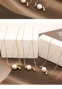 Detailed view of elegant snake chain necklaces with large round pearl pendants on white blocks