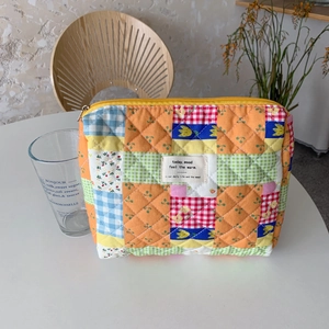 Detailed close-up of quilted floral patch makeup bag featuring colorful fabric textures