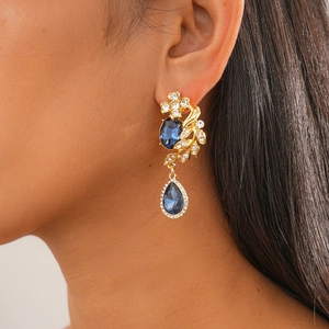 Close-up of vintage gold drop earrings with deep blue oval gemstones and sparkling diamonds