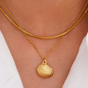 Close-up of double-layer 14k gold stainless steel necklace with shell pendant on neck