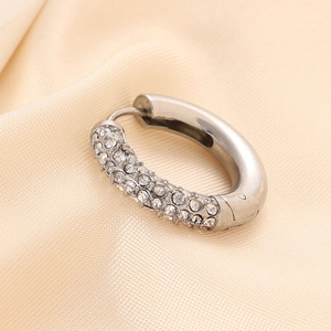 Detailed close-up of a silver-toned C-shaped hoop earring with shimmering pavé set zircons