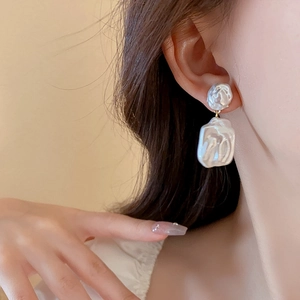 Close-up of star-shaped pearl earrings worn by a model in a warm setting