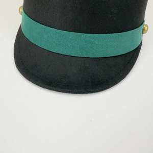 Detail of wool equestrian hat featuring dark green ribbon and gold button accents