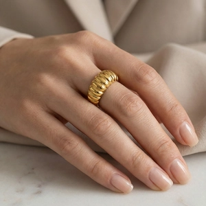 Macro shot of gold croissant dome ring with a polished textured finish on a model