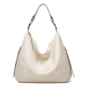 Detail shot of soft cream white PU leather texture and fringe tassels on a hobo shoulder bag
