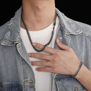 Close-up of gunmetal stainless steel cuban chain necklace and bracelet set on male model