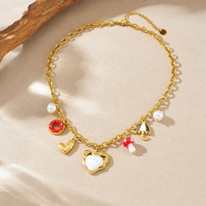 Collana placcata in oro con ciondoli a forma di fungo ciambella e cuore su sfondo beige