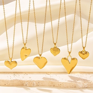 Set of six varied 18k gold plated heart pendants on elegant silk and stone background