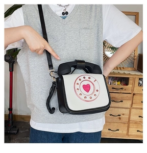 Creative vintage telephone crossbody bag with heart dial detail worn by model