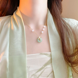 Détail du collier ginkgo plaqué or avec pendentif en jade vert porté au cou