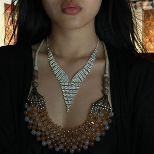 Elegant V-shaped silver rhinestone tassel necklace with orange beaded layers worn by model