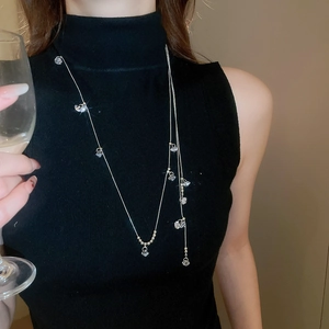 Détail d'un collier doré multicouche avec pendentifs en zircon sur col roulé noir