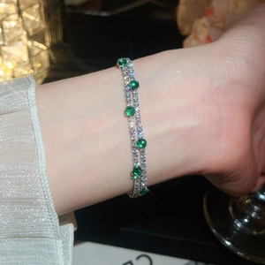 Detail of 18k gold plated double layer bracelet with green and white zircons on wrist.
