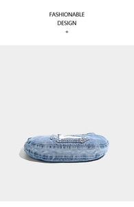 Detail of washed denim shoulder bag showing metal rivets and stitched fabric label