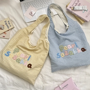 Close-up of light yellow and sky blue checkered tote bags with 3D letter embroidery