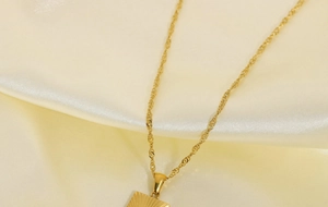 Dettaglio della collana con ciondolo sole placcata oro 18K su seta beige