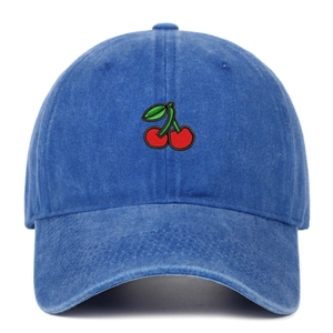 Detail of red cherry embroidery on dark blue washed denim baseball cap fabric