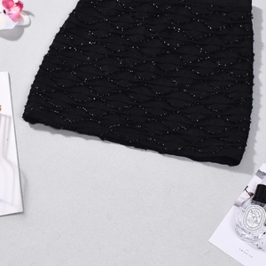 Détail de la mini-jupe noire avec paillettes argentées ondulées et texture plissée