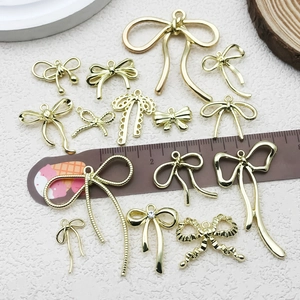 Golden bow-knot jewelry pendants with rhinestones shown on a light textured background
