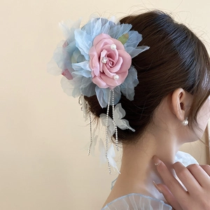 Détail de la pince à fleurs roses avec pétales en dentelle, papillon en tulle et franges
